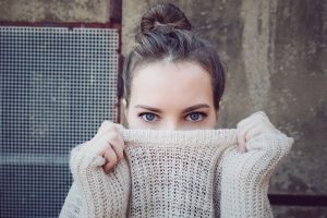 Woman hiding face behind knitwear